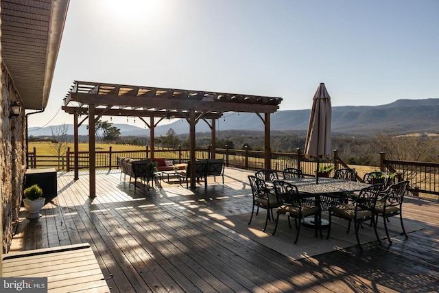 deck with a pergola, a mountain view, outdoor dining space, and a view of countryside