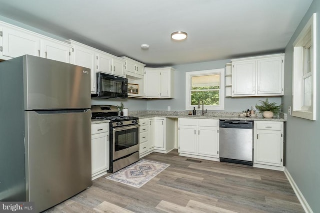 1055 Hacktown Rd, Keswick, VA 22947 - kitchen featuring stainless steel appliances, a sink, wood finished floors, light stone countertops, and white cabinets