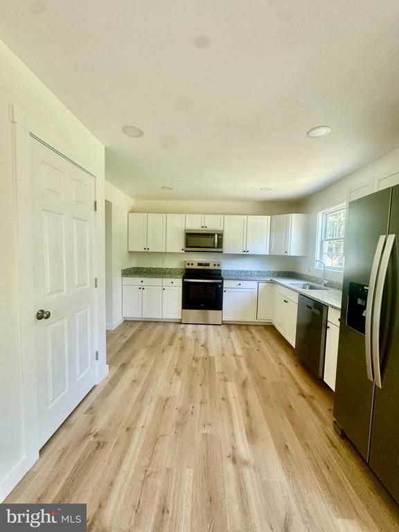 6273 Tatum Rd, Culpeper, VA 22701 - kitchen featuring appliances with stainless steel finishes, a sink, white cabinets, light wood-style floors, and light countertops