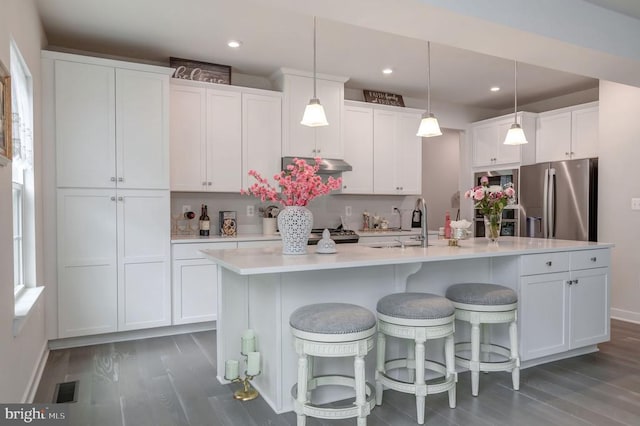 11316 Oakville Ln, Spotsylvania, VA 22551 - kitchen with stainless steel fridge with ice dispenser, wood finished floors, white cabinets, under cabinet range hood, and baseboards