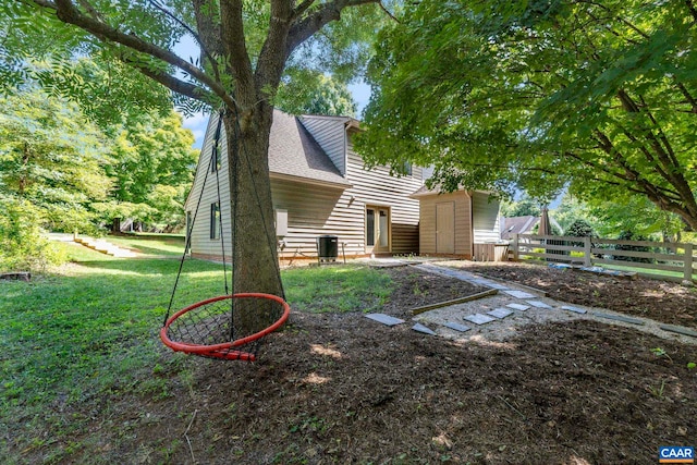 exterior space with central air condition unit, fence, and a lawn