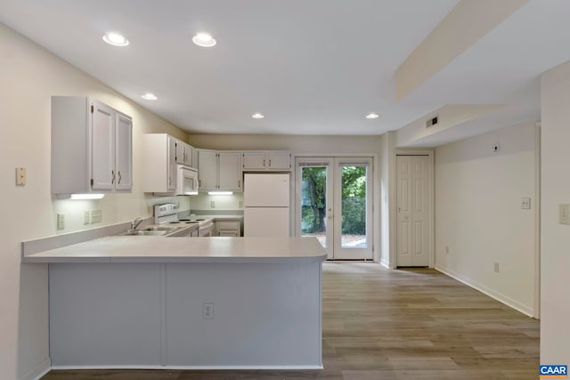 kitchen featuring a peninsula, light wood-type flooring, visible vents, white appliances, and light countertops