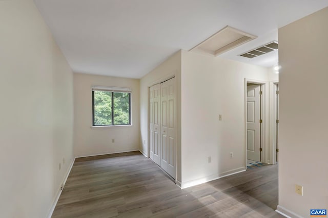 interior space featuring attic access, visible vents, wood finished floors, and baseboards