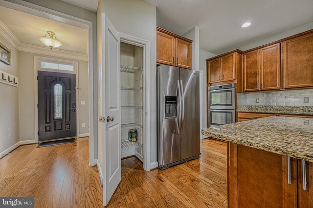 299 Sunset Loop, Mineral, VA 23117 - kitchen featuring stainless steel appliances, brown cabinets, light stone counters, light wood-type flooring, and decorative backsplash