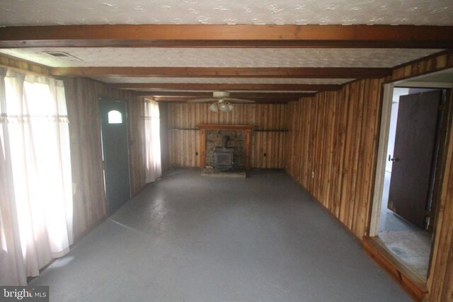  - basement with a wood stove, wood walls, and ceiling fan