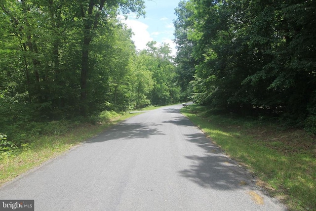 - view of asphalt street with a wooded view