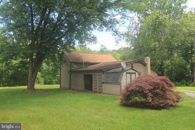  - view of side of property with a yard, a chimney, roof with shingles, and a storage unit