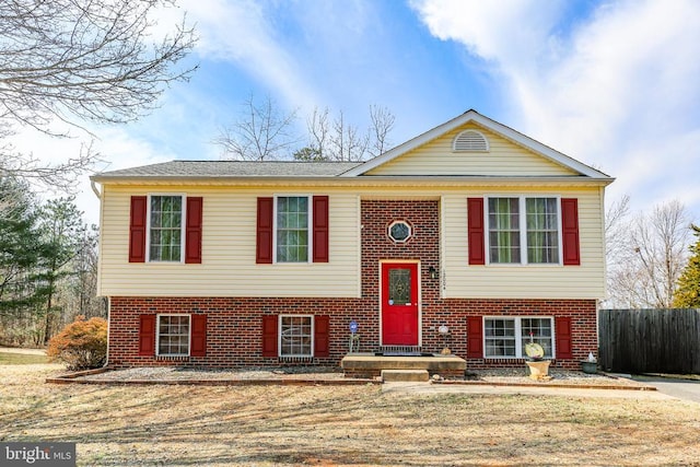 split foyer home featuring fence and brick siding