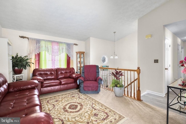 living area featuring carpet, a notable chandelier, a textured ceiling, and baseboards