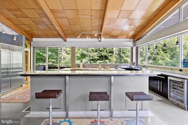  - kitchen with built in fridge, wine cooler, light stone countertops, finished concrete flooring, and wood ceiling