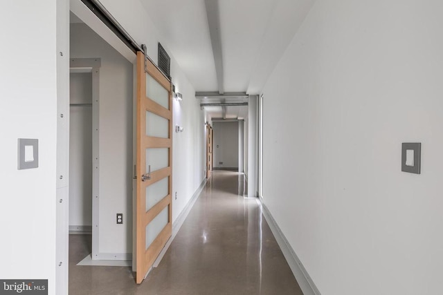 corridor with finished concrete floors, a barn door, and baseboards