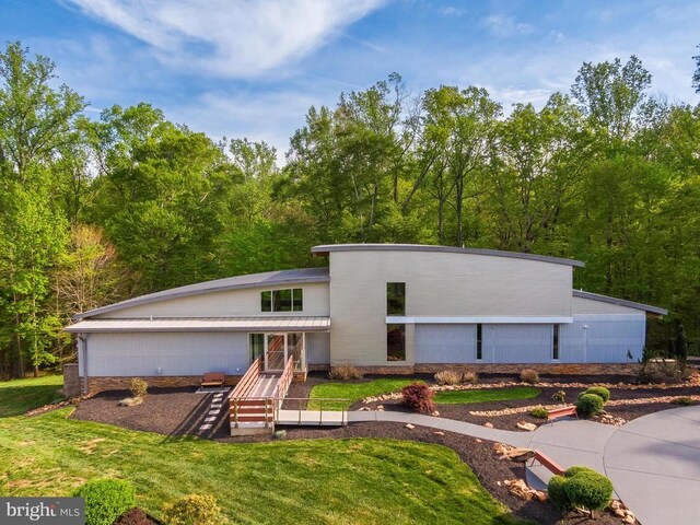  - mid-century home featuring a front yard and a view of trees