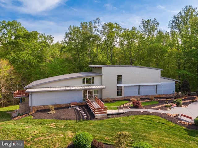back of house featuring a yard and a view of trees