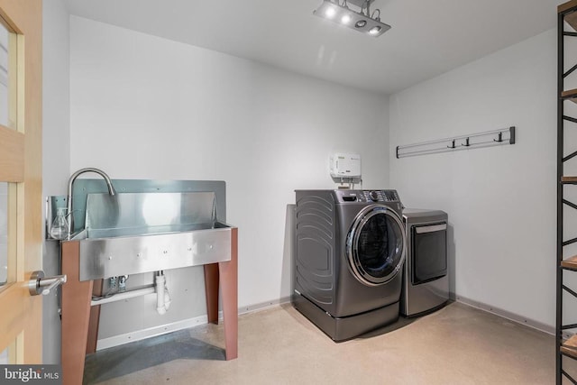 clothes washing area featuring laundry area, baseboards, and separate washer and dryer