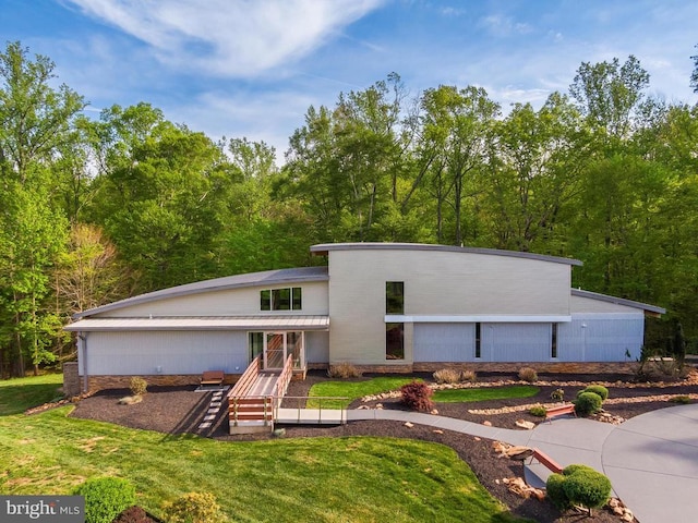back of property with a lawn and a forest view