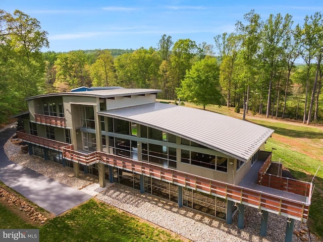 rear view of property featuring a view of trees and metal roof