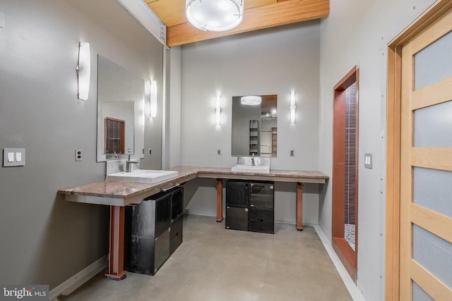 bathroom with a sink, finished concrete floors, and baseboards