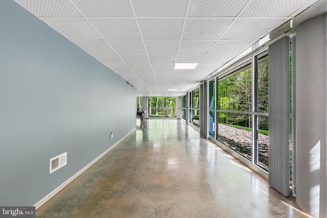 hallway featuring baseboards, expansive windows, visible vents, and finished concrete flooring