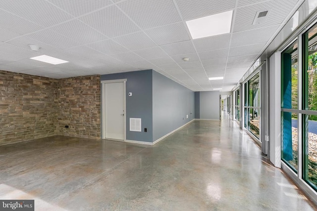 empty room with a paneled ceiling, baseboards, visible vents, and concrete floors