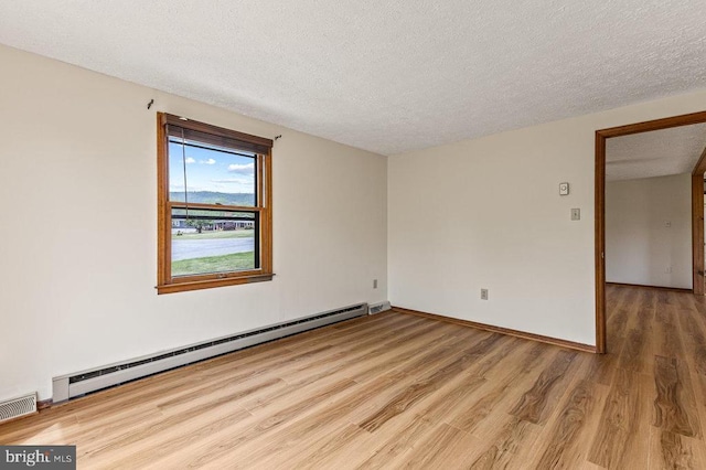 spare room with a baseboard heating unit, wood finished floors, a textured ceiling, and baseboards