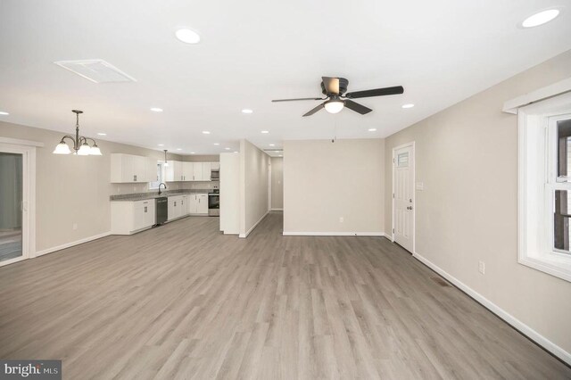 unfurnished living room featuring sink, ceiling fan with notable chandelier, and light hardwood / wood-style flooring