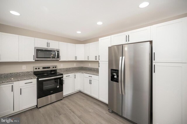 kitchen featuring appliances with stainless steel finishes, light stone countertops, and white cabinets