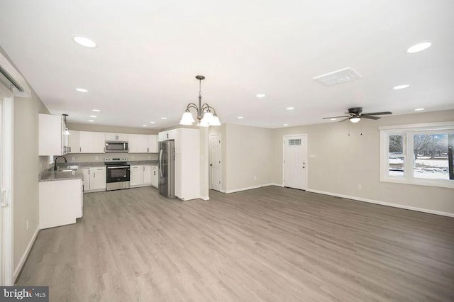 kitchen featuring pendant lighting, sink, stainless steel appliances, white cabinets, and light wood-type flooring