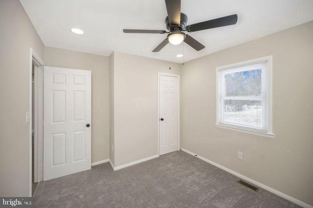 unfurnished bedroom with dark carpet, a closet, and ceiling fan