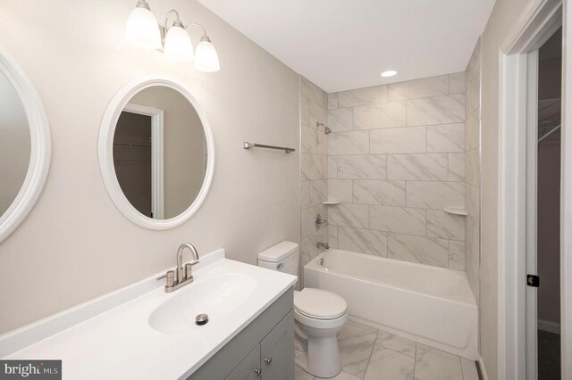 full bathroom featuring tiled shower / bath, vanity, and toilet