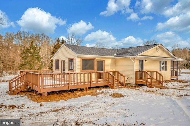 snow covered rear of property with a wooden deck