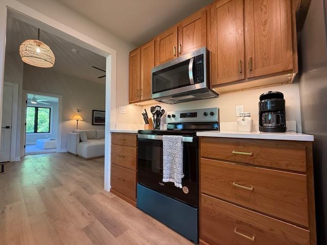 1201 Lakeshore Dr S, Louisa, VA 23093 - kitchen with stainless steel microwave, range with electric stovetop, light wood-type flooring, ceiling fan, and light countertops