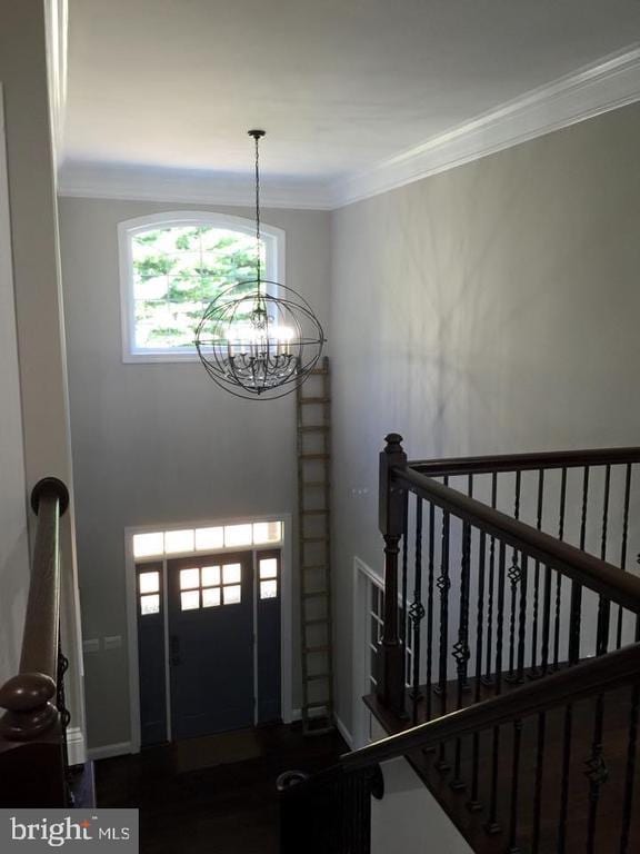  - entrance foyer featuring an inviting chandelier, crown molding, and baseboards