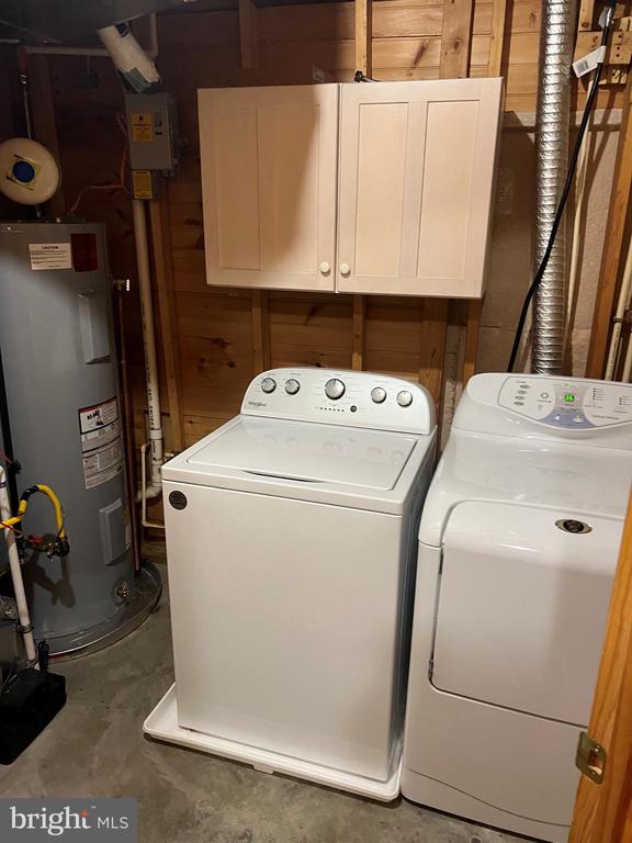 26536 Pennfields Dr, Orange, VA 22960 - clothes washing area featuring water heater, washer and clothes dryer, and cabinet space