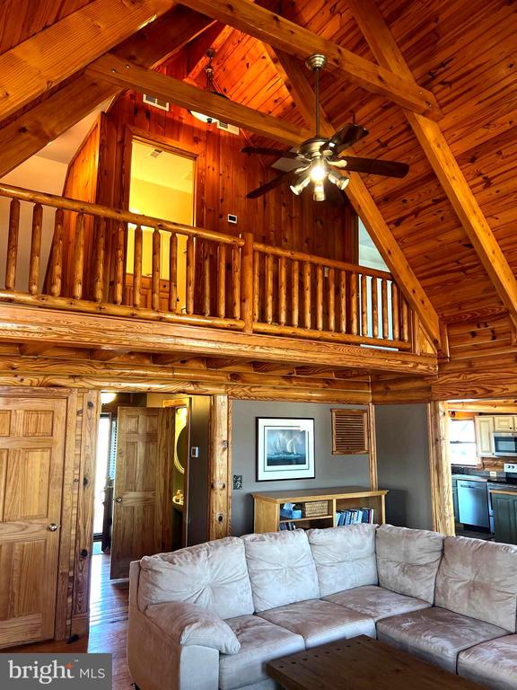26536 Pennfields Dr, Orange, VA 22960 - living area featuring high vaulted ceiling, wooden walls, a ceiling fan, beam ceiling, and wood finished floors