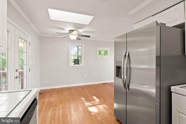 6314 Foster Rd, Spotsylvania, VA 22553 - kitchen with tile counters, stainless steel fridge with ice dispenser, a skylight, baseboards, and white cabinetry