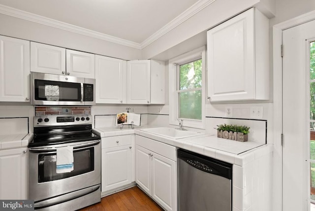 6314 Foster Rd, Spotsylvania, VA 22553 - kitchen featuring stainless steel appliances, a sink, tile countertops, crown molding, and white cabinets