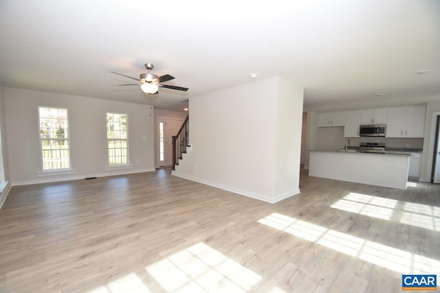 927 Jefferson Dr Unit Lm 279/1, Palmyra, VA 22963 - unfurnished living room featuring baseboards, ceiling fan, a sink, stairs, and light wood-type flooring