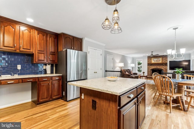 3803 Fallwood Ln, Fredericksburg, VA 22408 - kitchen with freestanding refrigerator, light wood finished floors, hanging light fixtures, open floor plan, and ornamental molding