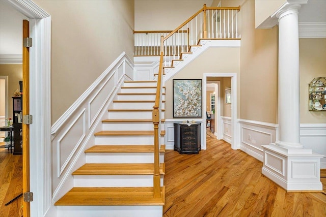 515 Legrande Ave, Waynesboro, VA 22980 - staircase with ornate columns, a decorative wall, wood finished floors, a high ceiling, and a wainscoted wall