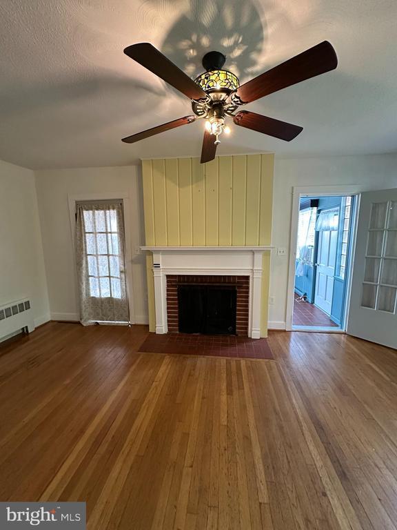2 Terrace Ln, Luray, VA 22835 - unfurnished living room featuring wood finished floors, a brick fireplace, and a ceiling fan