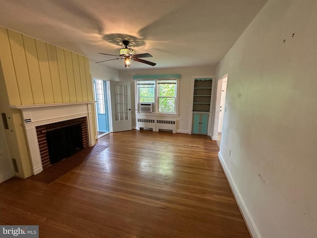2 Terrace Ln, Luray, VA 22835 - unfurnished living room featuring radiator heating unit, wood finished floors, a ceiling fan, cooling unit, and a brick fireplace