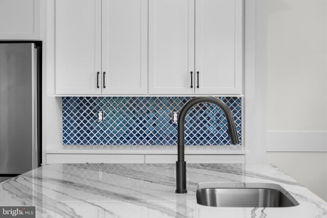  - kitchen view of freestanding refrigerator, backsplash, and light stone counters