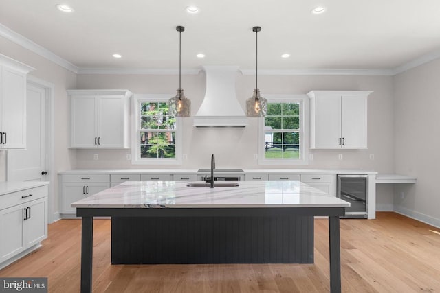 - kitchen featuring wine cooler, custom exhaust hood, white cabinetry, plenty of natural light, and ornamental molding