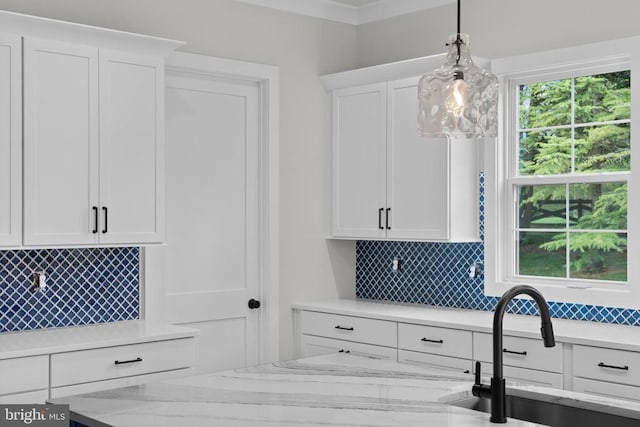  - kitchen with white cabinetry, backsplash, decorative light fixtures, and light stone counters