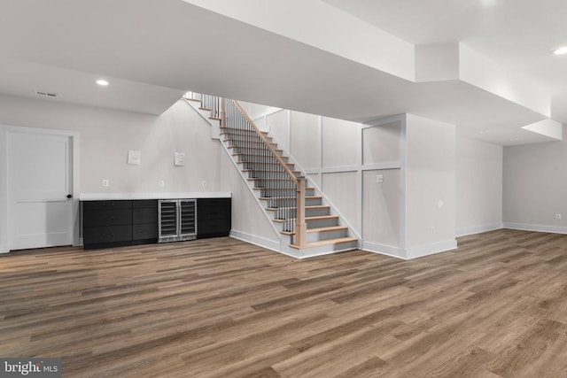  - below grade area featuring wine cooler, stairway, wood finished floors, and recessed lighting