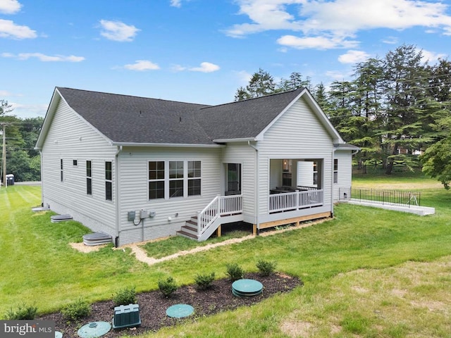  - view of front facade with a deck, a shingled roof, and a front lawn