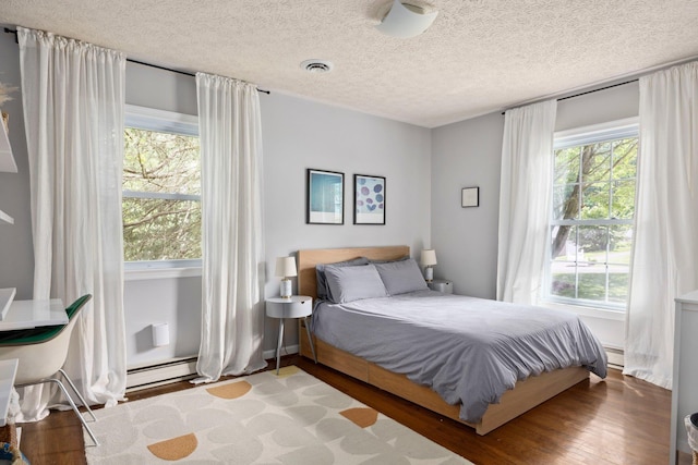 1233 Pinehurst Rd, Staunton, VA 24401 - bedroom featuring wood finished floors, baseboard heating, a textured ceiling, and a baseboard radiator