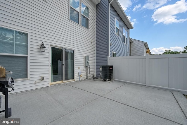 rear view of house with a patio, fence, and central AC unit