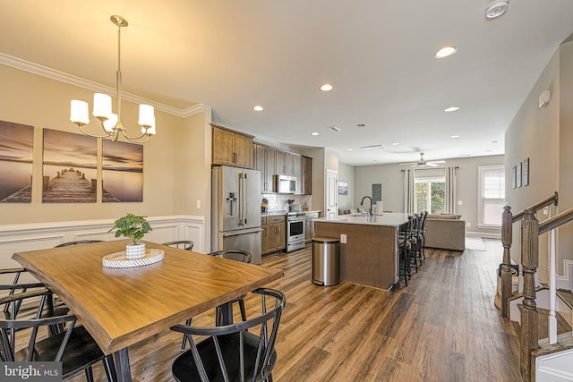 dining area featuring dark wood finished floors, a chandelier, ceiling fan, ornamental molding, and recessed lighting
