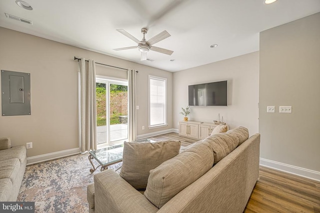 living room featuring electric panel, baseboards, ceiling fan, recessed lighting, and wood finished floors